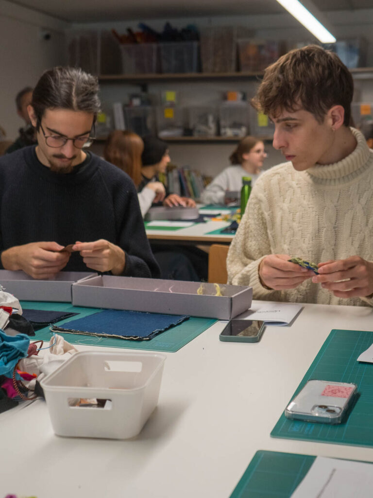 two men sitting at a table looking at their phones