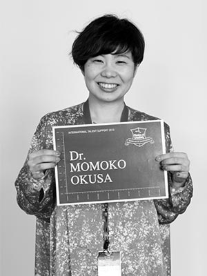 a woman holding a sign that says dr momko okusa