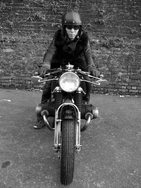 a man riding on the back of a motorcycle down a street