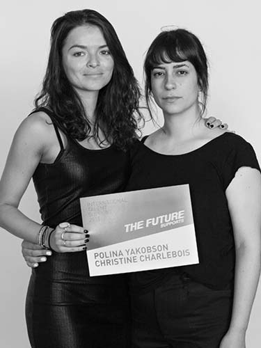 two women standing next to each other holding a sign