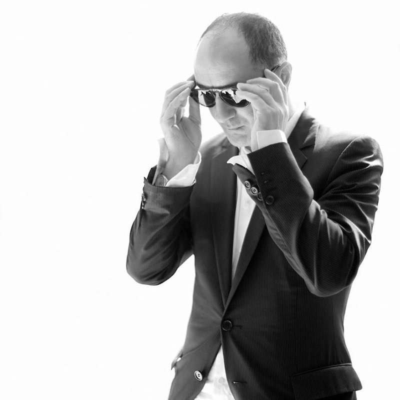 a man in a suit and sunglasses talking on a cell phone