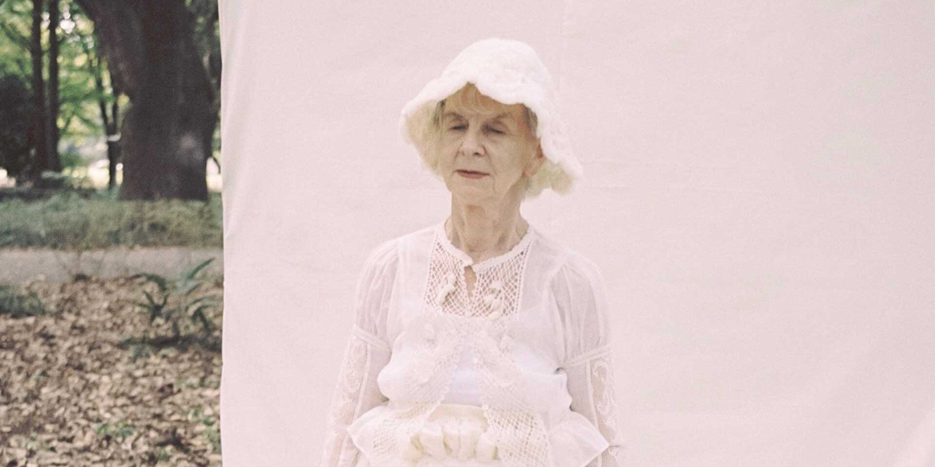 an old woman in a white dress and hat