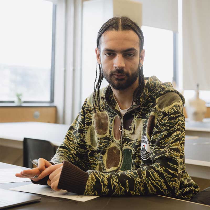 a man with dreadlocks sitting at a desk