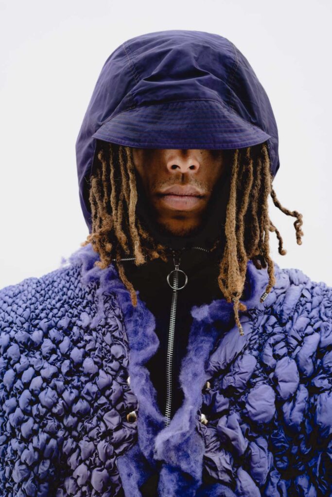 a man with dreadlocks wearing a blue jacket