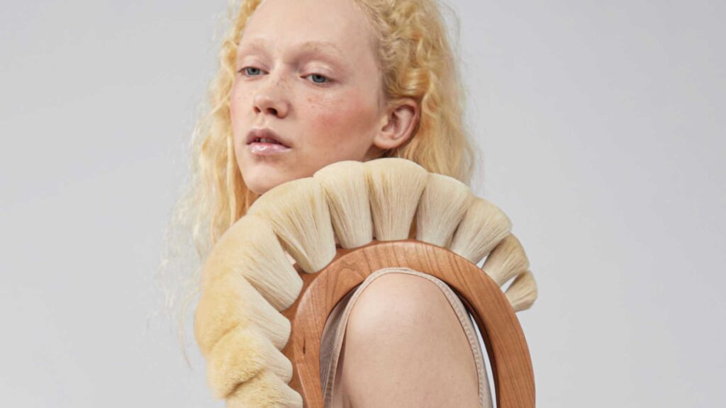 a woman with blonde hair holding a round mirror