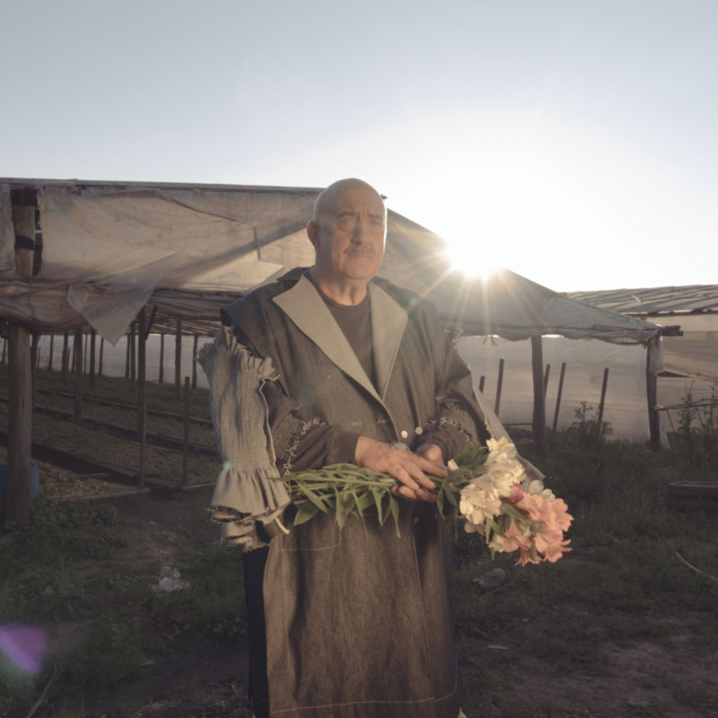 a man standing in a field holding a bouquet of flowers