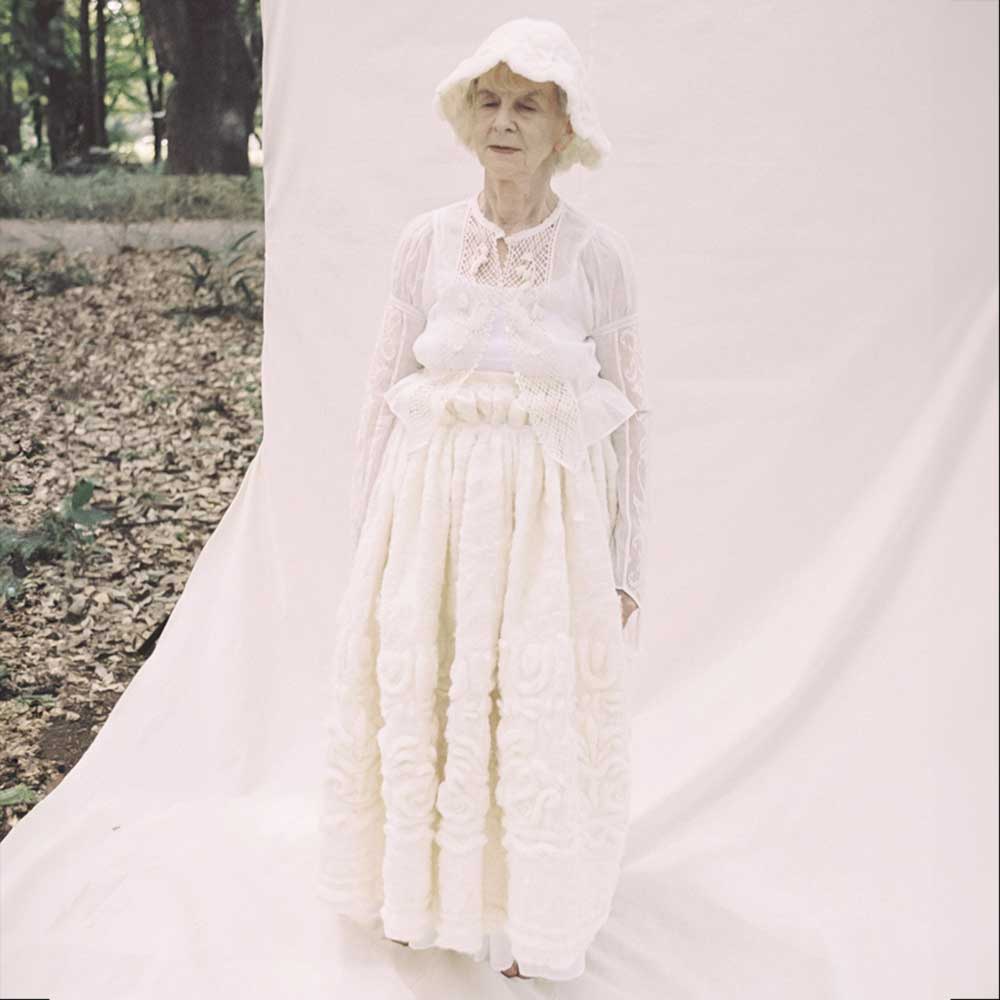 a woman in a white dress standing in front of a white backdrop